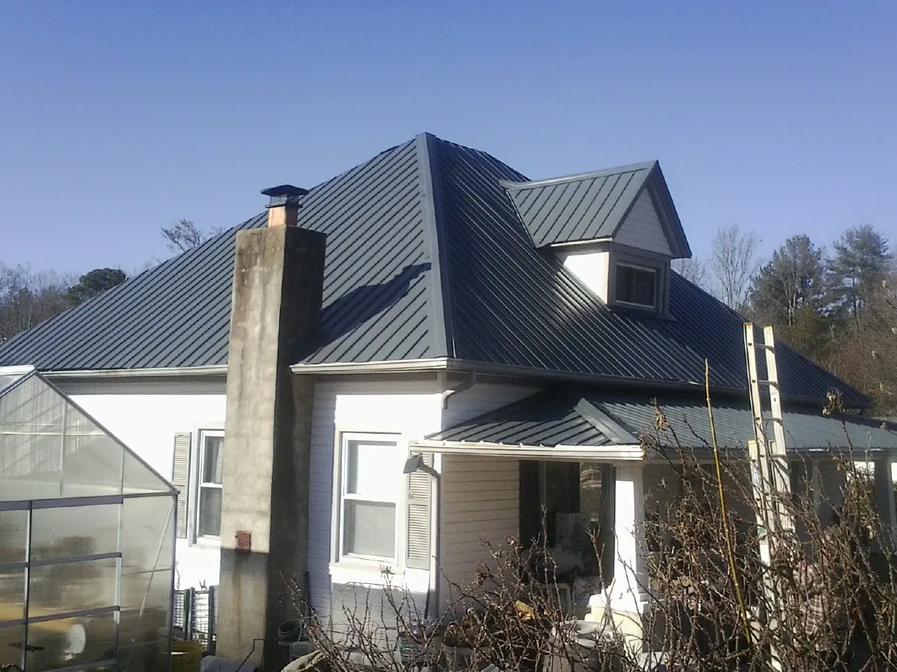 Dark blue standing seam metal roof on a white farmhouse with dormer — Slate & Tile Roof Repair by Roofing Brothers in Leeton