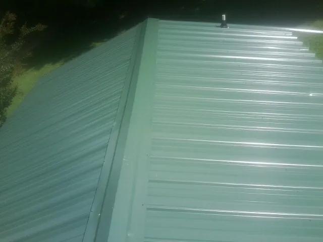 New green metal panels meeting at the ridge of a roof — Flat Roof Repair work by our crew in Leeton