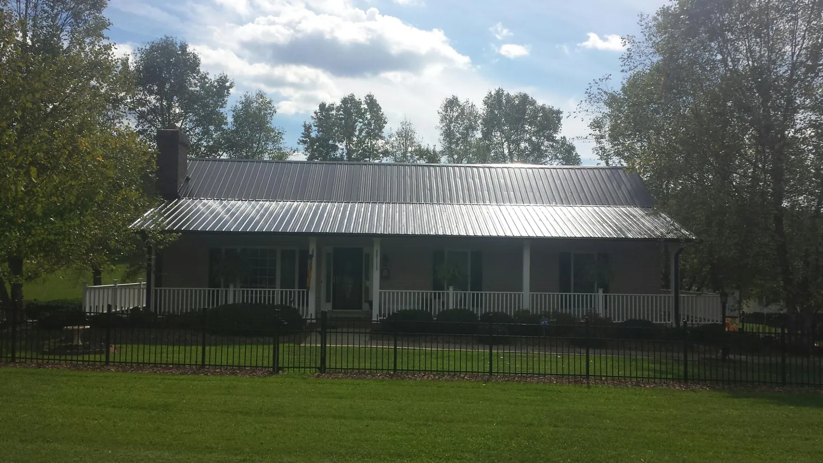 Gray metal roof on a brick ranch with a full width front porch — Gutter Guard Installation work by our crew in Leeton