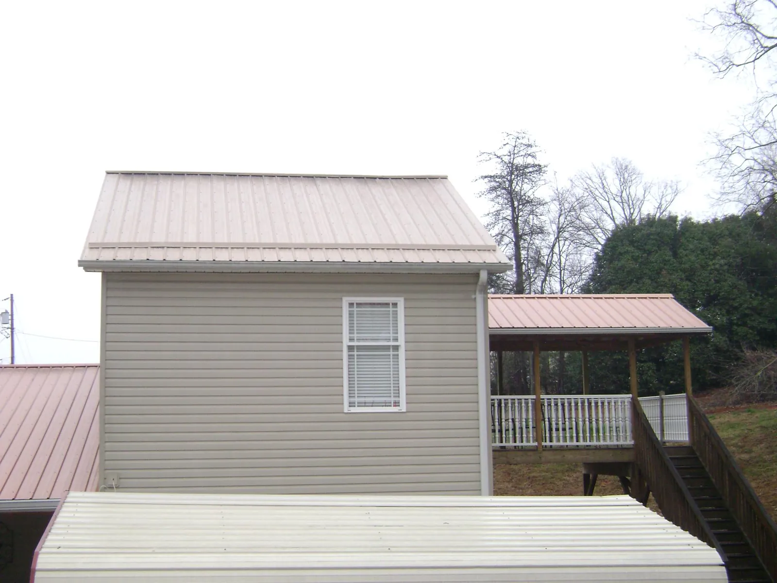 Tan metal roofs on a two story addition and attached porch, from a Roof Replacement job in Leeton