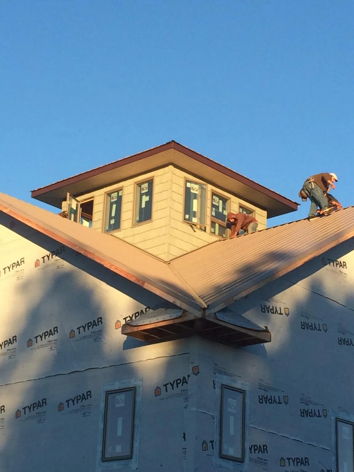 Roofers working around a rooftop cupola on a new metal roof at sunset — Roof Waterproofing in Leeton by Roofing Brothers